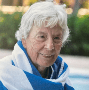 gayle wampler. elderly lady with white hair. she's wearing a blue and white towel around her shoulders. she has a sweet smile.